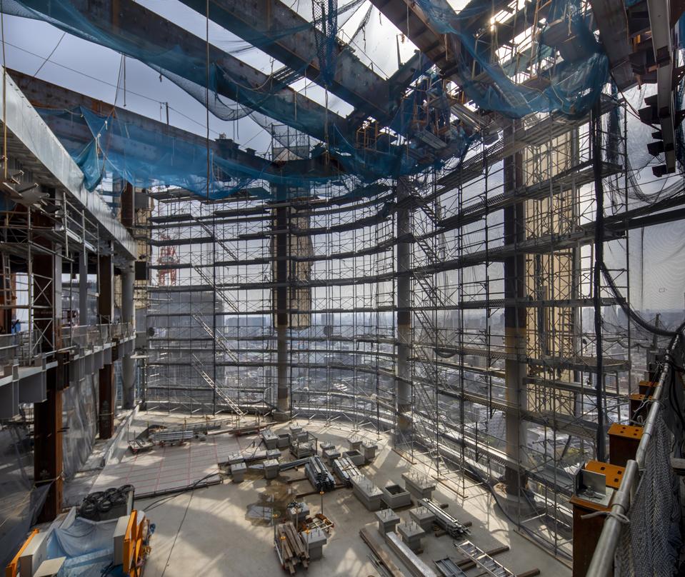 Interior of the Takanawa Gateway City building under construction, featuring scaffolding, steel beams, and construction materials.