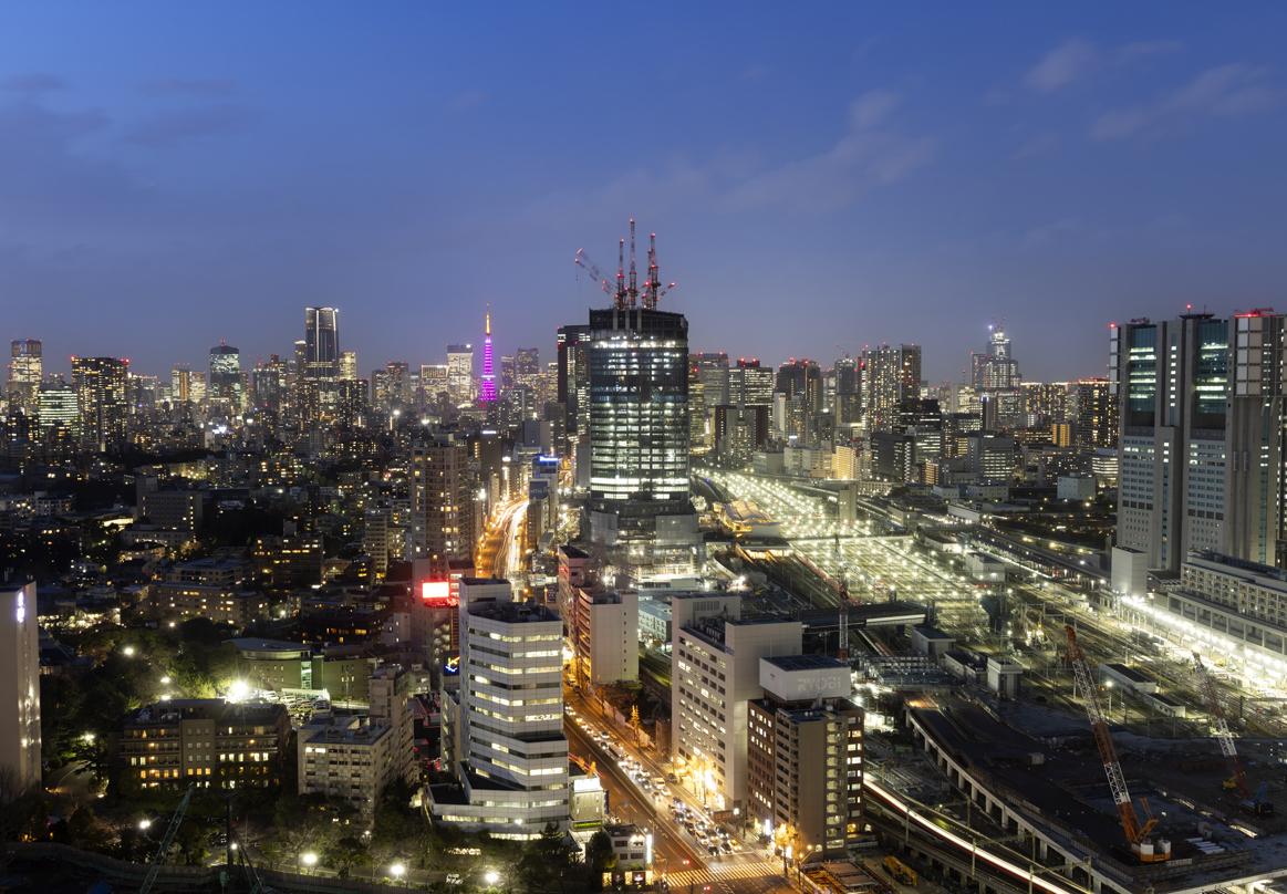 Global Gateway Shinagawa construction site at night, surrounded by illuminated urban cityscape.
