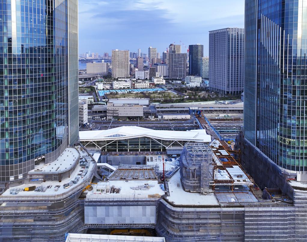Takanawa Gateway City construction site with two skyscrapers, glass facades, and urban landscape in the background.