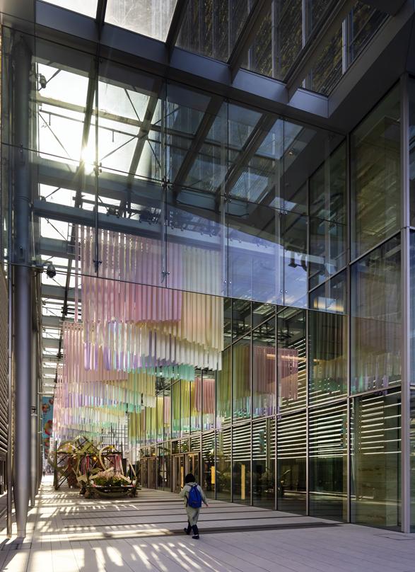 Modern interior of Tokyo Midtown Yaesu with large glass panels, featuring colorful hanging art installations and natural light streaming in.