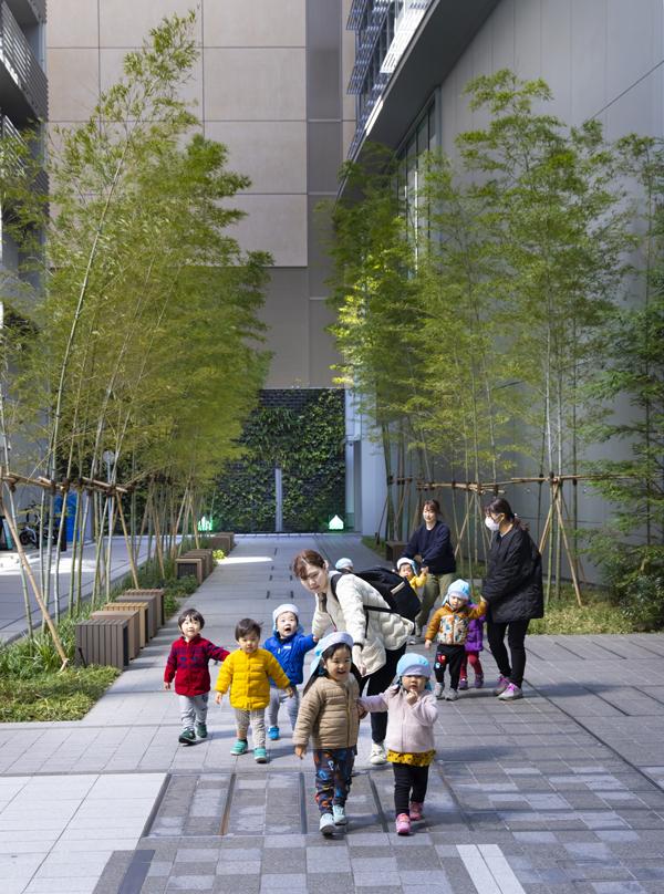 Children and their caregivers walk through a landscaped area with bamboo plants at Tokyo Midtown Yaesu, enjoying the outdoor space.